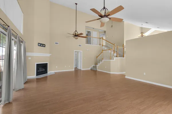 a view of an empty room with window and wooden floor
