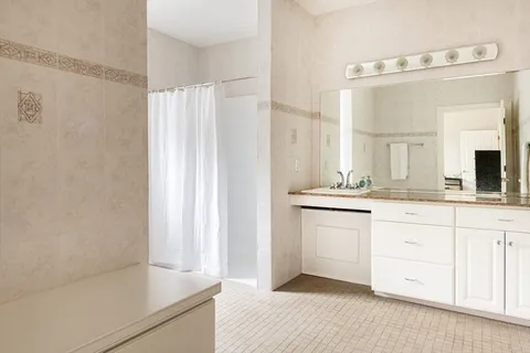 a spacious bathroom with a granite countertop sink and a mirror