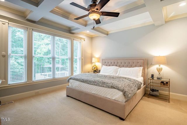 a spacious bedroom with a large bed and a chandelier fan