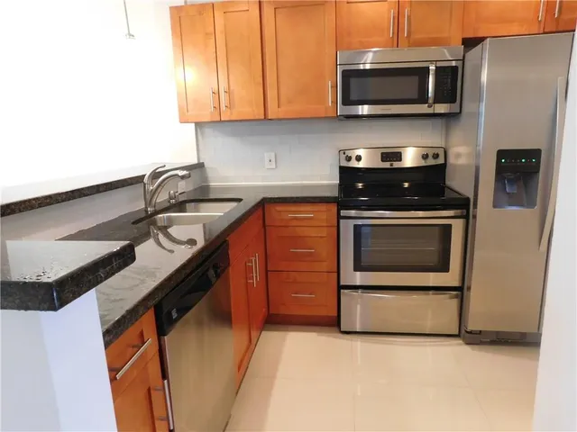 a kitchen with stainless steel appliances a stove a microwave a sink and cabinets