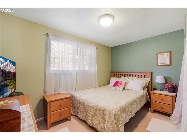 a bedroom with a bed and a flat tv screen on dresser