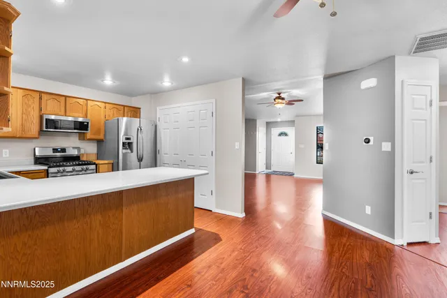 an empty room with wooden floor a chandelier fan and windows