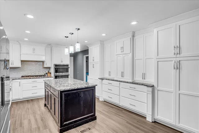 a kitchen with stainless steel appliances granite countertop white cabinets and window
