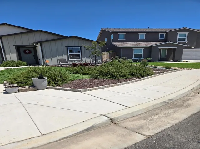front view of a brick house with a small yard and potted plants