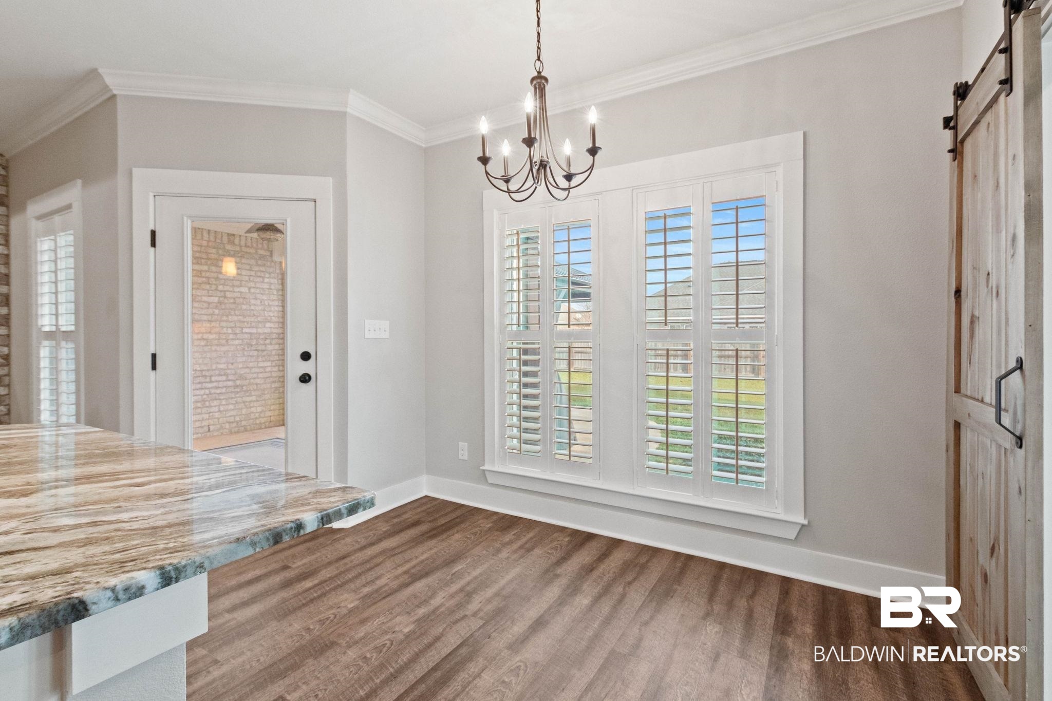 17376 Bankhead Boulevard Fairhope, AL 36532 - Photo 29 of 73 Unfurnished dining area featuring a barn door, crown molding, dark wood-style floors, and a chandelier