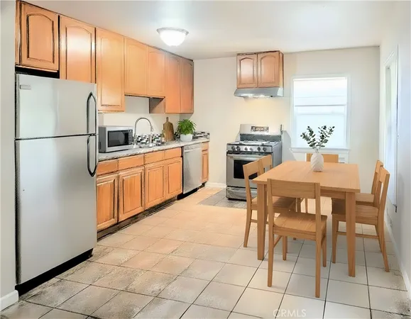 a kitchen with stainless steel appliances granite countertop a stove a sink a refrigerator and a refrigerator with wooden cabinets