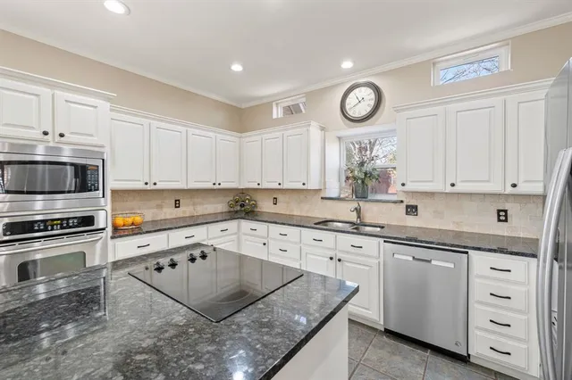 a kitchen with granite countertop a sink cabinets stainless steel appliances and a window