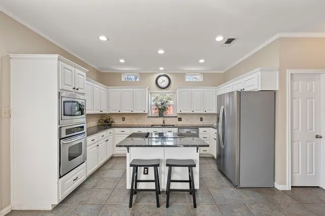 a kitchen with a refrigerator a stove top oven a sink and cabinets