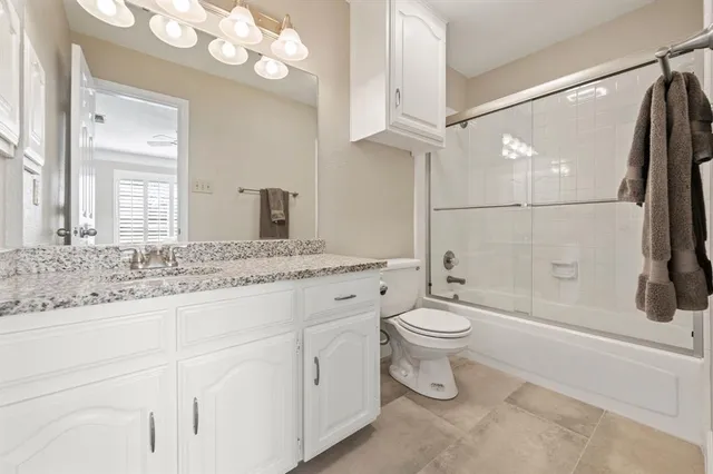 a bathroom with a granite countertop sink a toilet and a mirror
