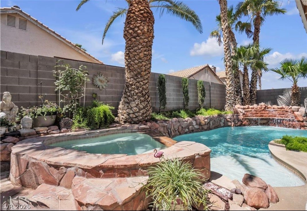 6429 Winding Ridge Las Vegas, NV 89156 - Photo 22 of 22 An inviting backyard oasis offers a rock-scaped pool and integrated spa, framed by mature palms.