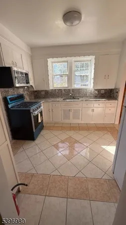a large kitchen with granite countertop a stove a sink a counter space and cabinets