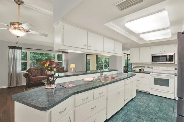 a kitchen with white cabinets a sink dishwasher and a stove with wooden floor