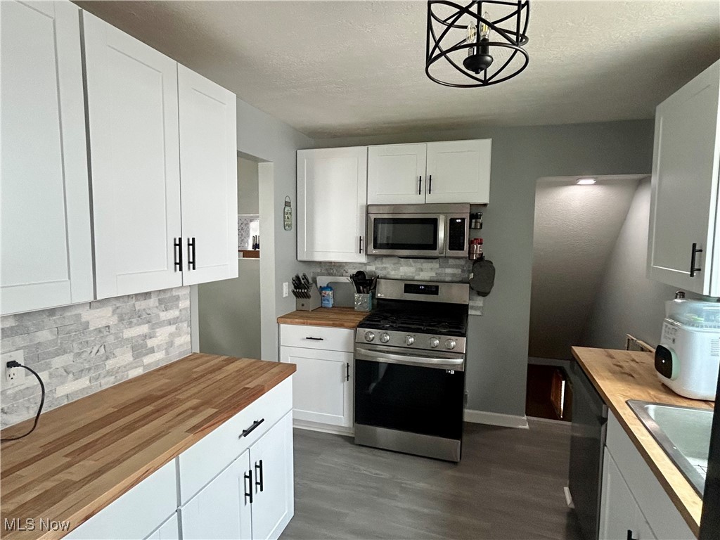 935 Lilly Road Alliance, OH 44601 - Photo 15 of 31 Kitchen with butcher block counters, appliances with stainless steel finishes, backsplash, dark wood-style floors, and white cabinetry