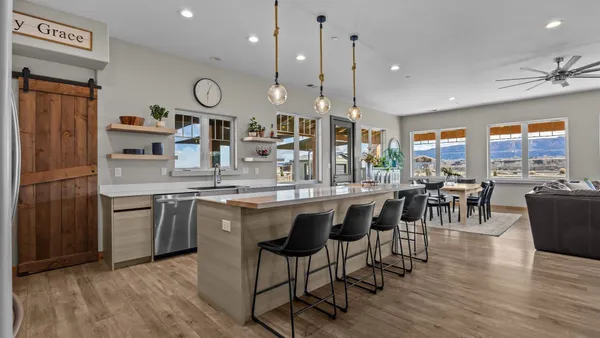 a kitchen with stainless steel appliances granite countertop a stove a refrigerator a kitchen island a dining table and chairs with wooden floor