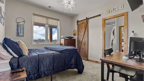 a bedroom with a bed table chair and a flat tv screen