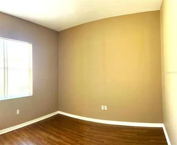 a view of a big room with wooden floor and a window