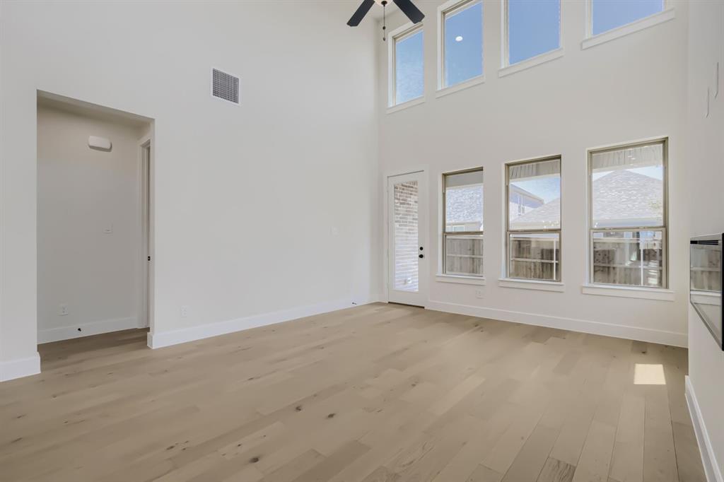 824 Stone Grv Road Lavon, TX 75166 - Photo 5 of 26 Two-story living area featuring wood-finish flooring, a contemporary ceiling fan, and a wall of windows