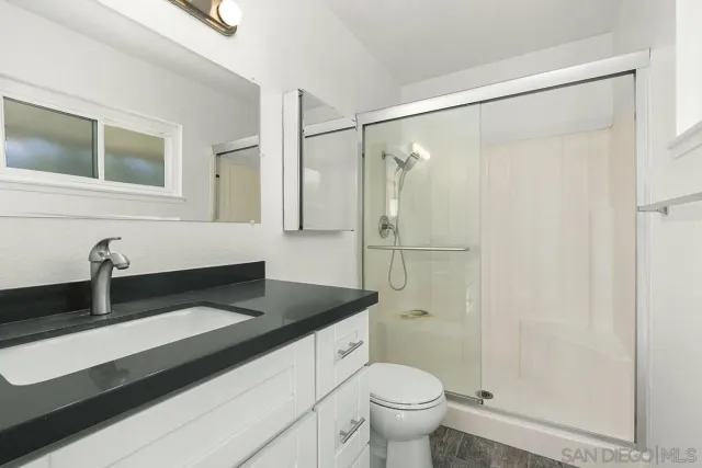 a bathroom with a granite countertop sink toilet and shower