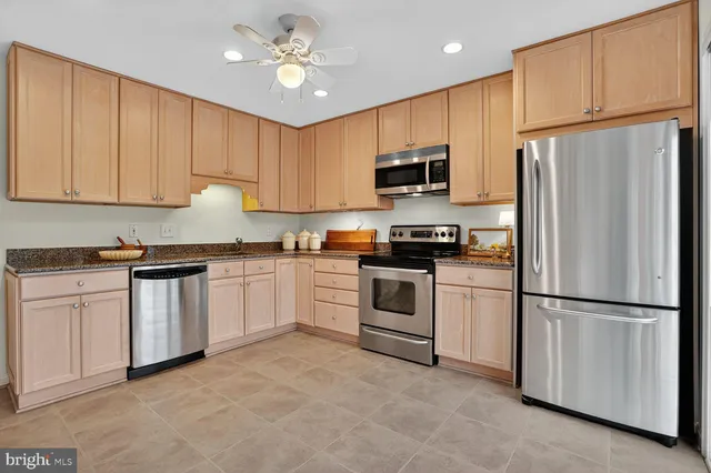 a kitchen with white cabinets stainless steel appliances and a refrigerator