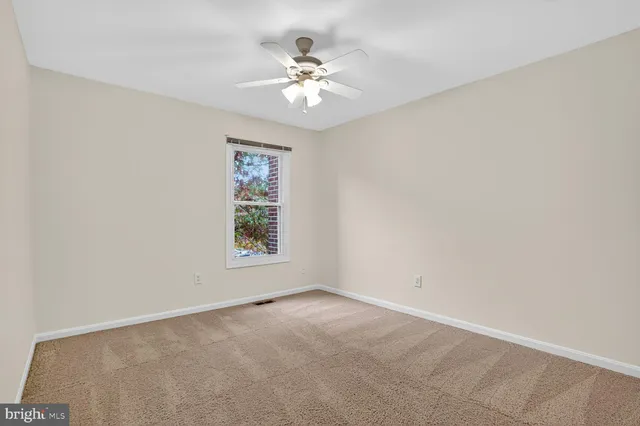 an empty room with windows and chandelier fan