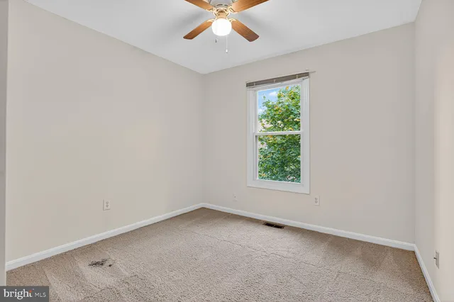 an empty room with a window and a fan