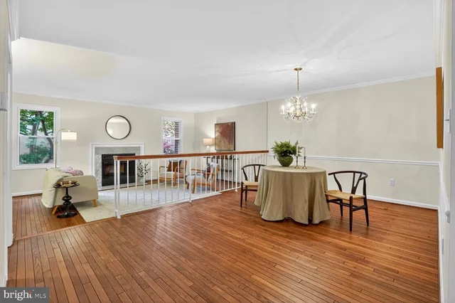 a dining room with wooden floor a chandelier a wooden table and chairs