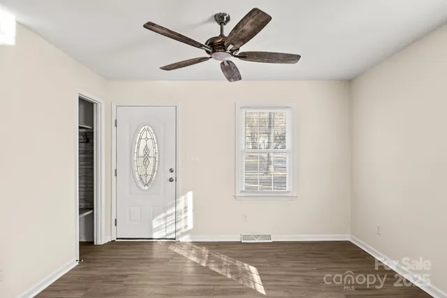 a view of empty room with wooden floor and ceiling fan