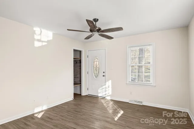 a view of an empty room with wooden floor and a window