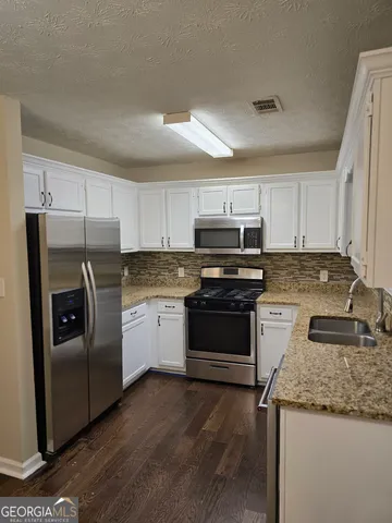 a kitchen with granite countertop stainless steel appliances and white cabinets