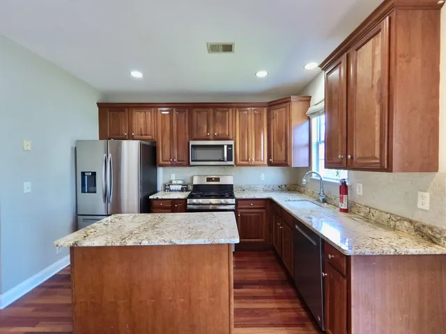 a kitchen with granite countertop stainless steel appliances a refrigerator sink stove microwave and cabinets