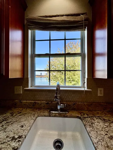 a bathroom with a granite countertop sink and a window