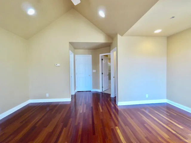 a view of an empty room with wooden floor and a ceiling fan