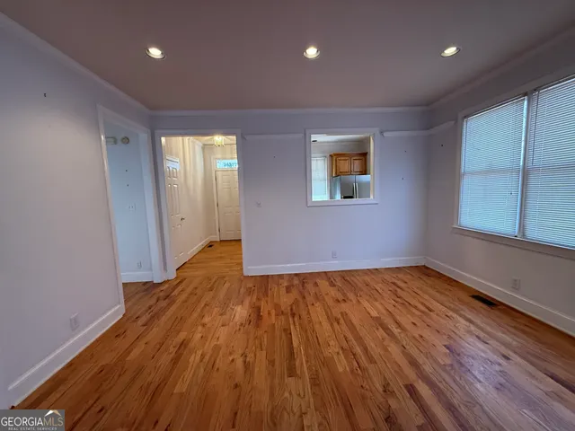 a view of an empty room with wooden floor and a window