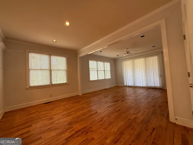 a view of an empty room with wooden floor and a window