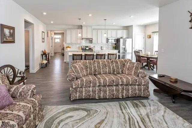 a living room with furniture and a kitchen view with wooden floor
