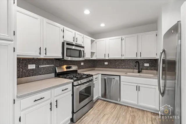 a kitchen with white cabinets stainless steel appliances and sink