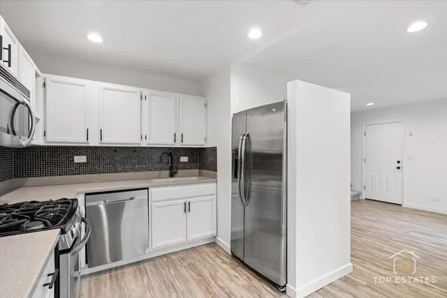 a kitchen with a sink a refrigerator and white cabinets