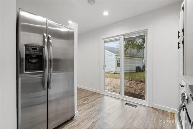 a view of a refrigerator in kitchen and an empty room