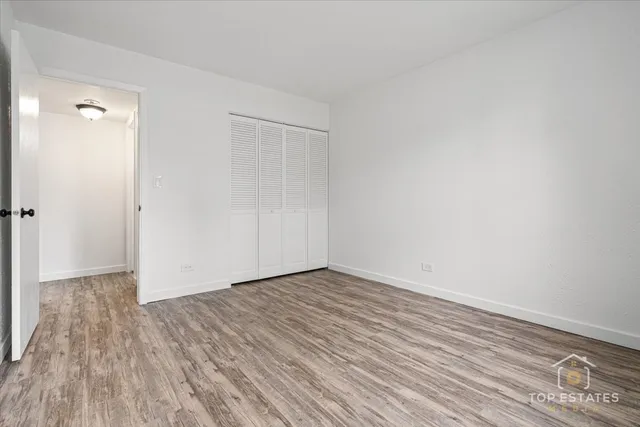 a view of an empty room with closet and wooden floor
