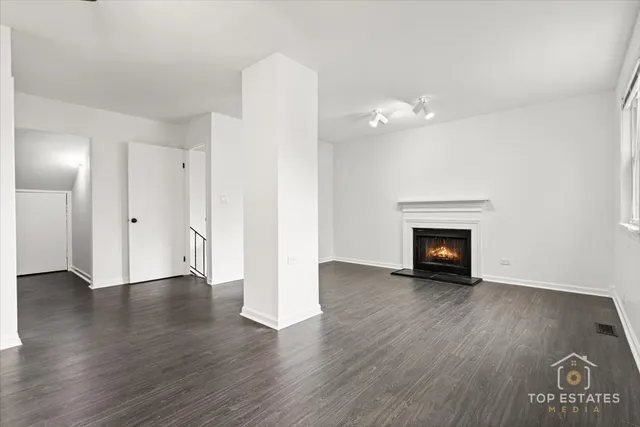 a view of an empty room with wooden floor and a fireplace