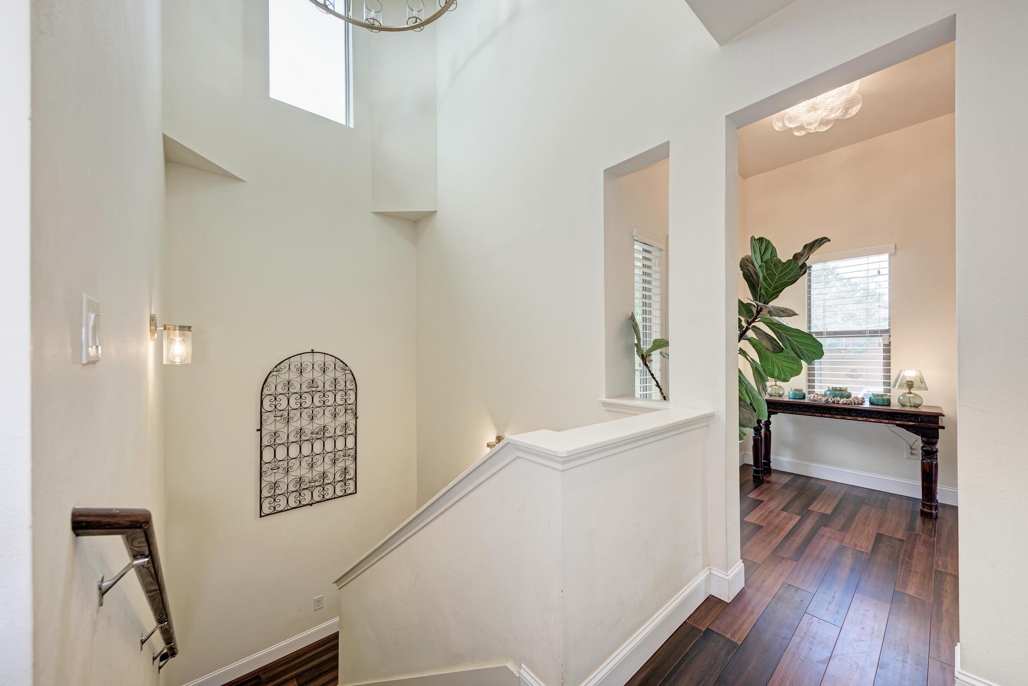 2605 Indian Creek Road Austin, TX 78734 - Photo 19 of 33 Multi-level interior featuring a contemporary chandelier, high ceilings, a prominent staircase with dark wood-finish handrail, and sconce lighting