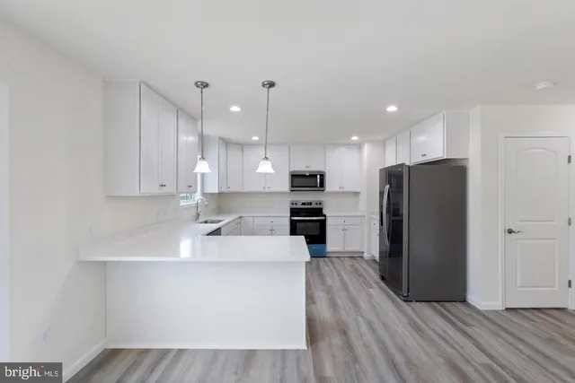 a kitchen with stainless steel appliances granite countertop a refrigerator a sink a stove and oven with wooden floor