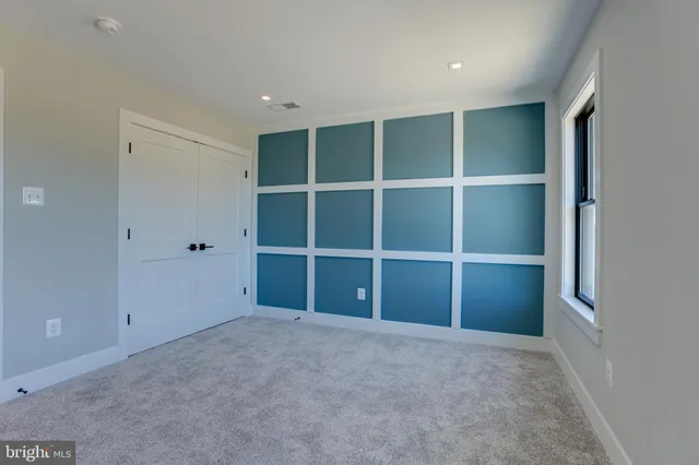 a view of an empty room with a closet and wooden shelves
