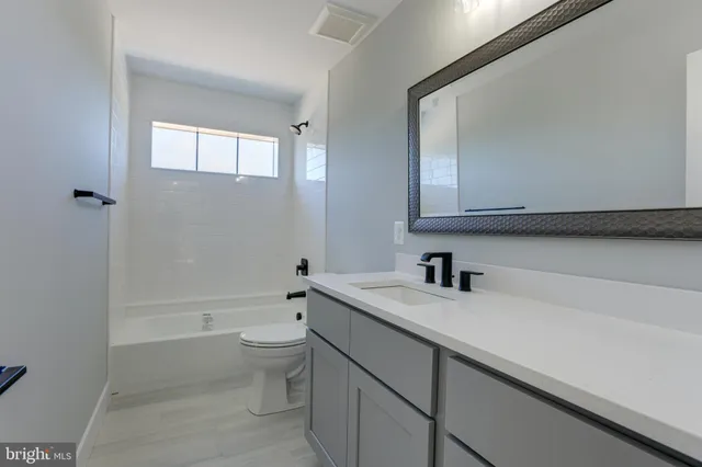 a bathroom with a granite countertop sink a toilet and bathtub