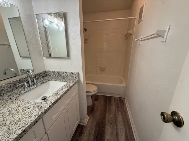a bathroom with a granite countertop sink a toilet and shower