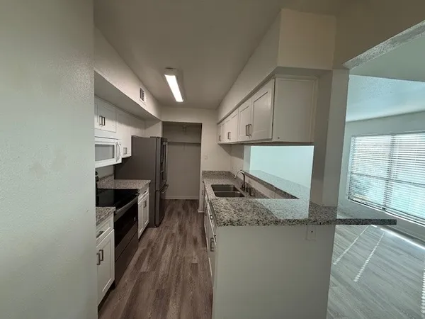 a kitchen with granite countertop sink stove and refrigerator