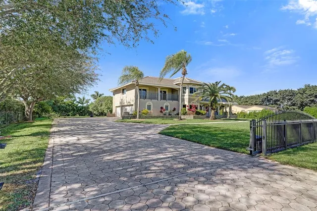 a view of a white house with a big yard and large trees