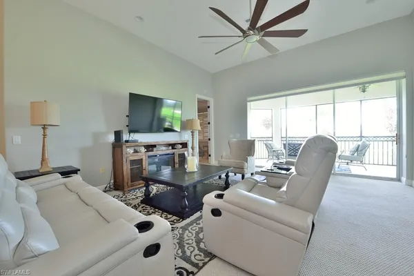 a living room with furniture a flat screen tv and a large window