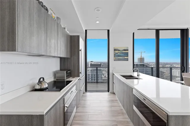 a large kitchen with kitchen island a large window a sink and stainless steel appliances