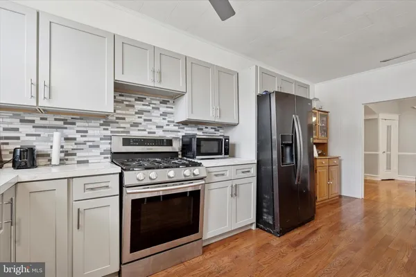 a kitchen with cabinets stainless steel appliances and wooden floor